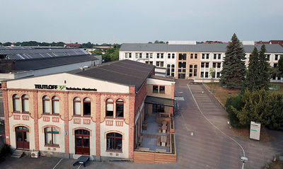 Luftaufnahme Gebäudekomplex mit Terrasse, Parkplatz, Grünfläche tagsüber